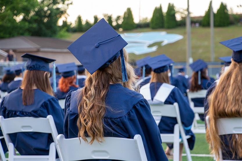 Students graduate outside on a football field